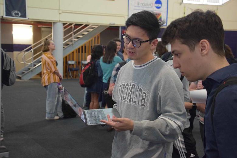 student holding laptop and talking at ACURA fair 2023